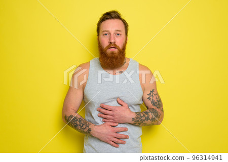 Suffering man with beard and tattoos has stomach ache 96314941