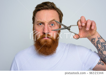 Serious man with scissors is ready to cut the beard 96315344