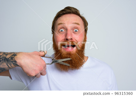 Unhappy man with scissors doees not want to cut the beard Unhappy man with scissors doees not want to cut the beard 96315360
