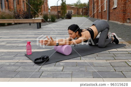 Fitness woman doing exercises with a massage roller on the street Fitness woman doing exercises with a massage roller on the street 96315628