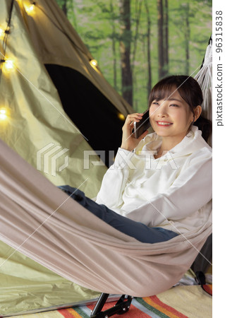 Home time: A woman using a smartphone while relaxing in a hammock Home time: A woman using a smartphone while relaxing in a hammock 96315838