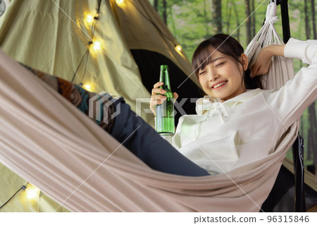 居家時光：一位女士在吊床上放鬆地喝著啤酒 96315846