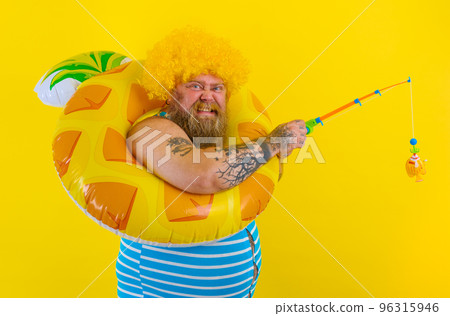 Fat happy man with wig in head plays with the fishing rod 96315946