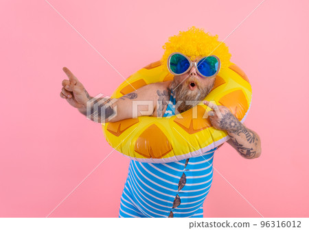 Fat amazed man with wig in head is ready to swim with a donut lifesaver Fat amazed man with wig in head is ready to swim with a donut lifesaver 96316012