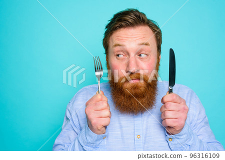Man with tattoos is ready to eat with cutlery in hand Man with tattoos is ready to eat with cutlery in hand 96316109