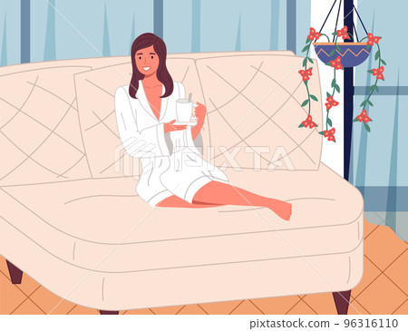 Beautiful young girl in terry white bathrobe on the couch with cup of drink. Spa treatments 96316110