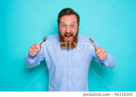 Hungry man with tattoos is ready to eat with cutlery in hand Hungry man with tattoos is ready to eat with cutlery in hand 96316205