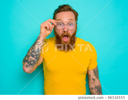 Man with yellow t-shirt and beard is shocked about something Man with yellow t-shirt and beard is shocked about something 96316555