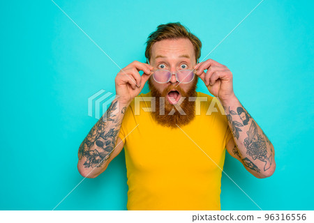 Man with yellow t-shirt and beard is shocked about something Man with yellow t-shirt and beard is shocked about something 96316556