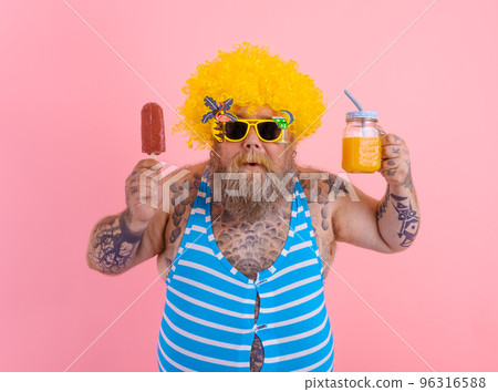 Fat surprised man with beard and wig eats a popsicle and drinks a juice fruit Fat surprised man with beard and wig eats a popsicle and drinks a juice fruit 96316588