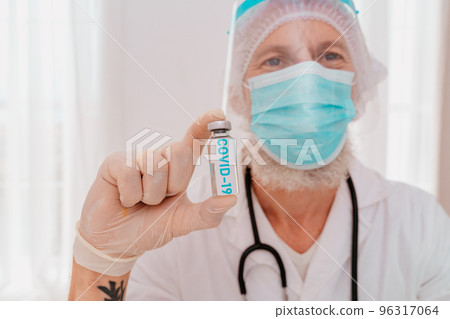 Doctor with mask and syringe is ready to administer the vaccine against covid 19 Doctor with mask and syringe is ready to administer the vaccine against covid 19 96317064