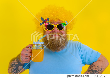 Fat happy man with wig in head and sunglasses drinks a fruit juice 96317178