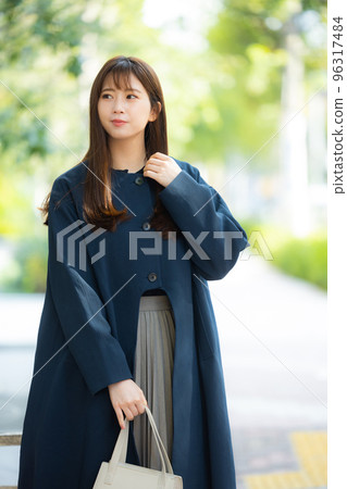 A woman in a coat walking outdoors A woman in a coat walking outdoors 96317484