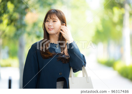 穿著外套在戶外散步的女人 穿著外套在戶外散步的女人 96317486