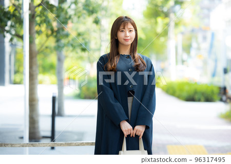 A woman in a coat walking outdoors 96317495