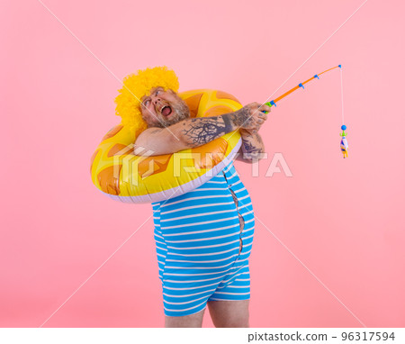 Fat stressed man with wig in head plays with the fishing rod Fat stressed man with wig in head plays with the fishing rod 96317594