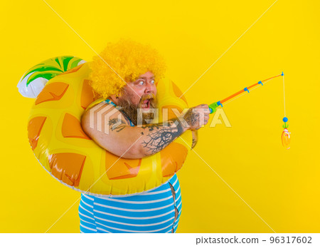 Fat amazed man with wig in head plays with the fishing rod 96317602