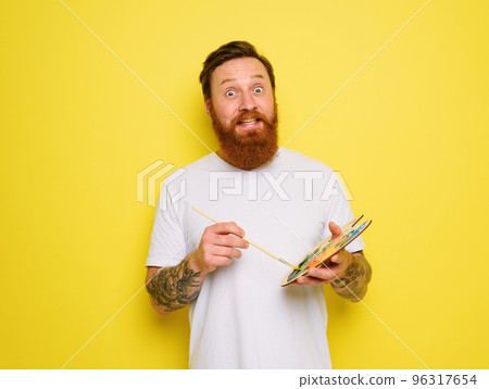 Doubter man with beard and tattoo is ready to draw with brushes 96317654