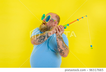 Fat man with beard and sunglasses have fun with the fishing rod Fat man with beard and sunglasses have fun with the fishing rod 96317665