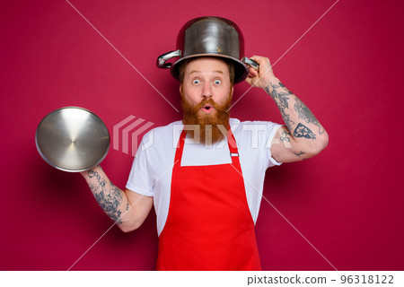 wondered chef with beard and red apron plays with pot 96318122