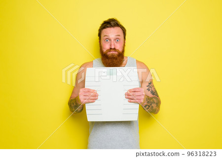 Man with beard and tattoos holds an electronic balance 96318223