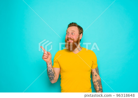 Man with yellow t-shirt and beard is shocked about something 96318648
