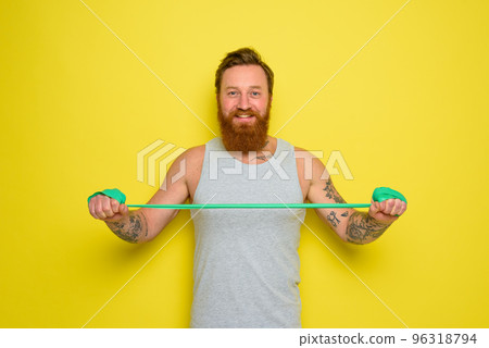 Man with beard and tattoos trains with a rubber band 96318794