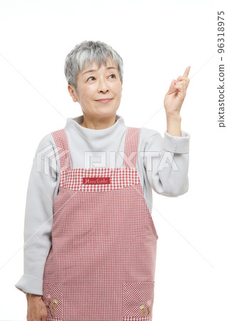Senior woman pointing in an apron 96318975