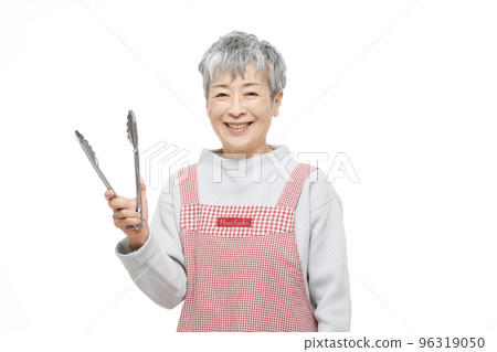 Senior woman with tongs in an apron 96319050