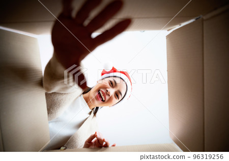 Happy young asian woman wearing christmas hat and unpacking gift box 96319256