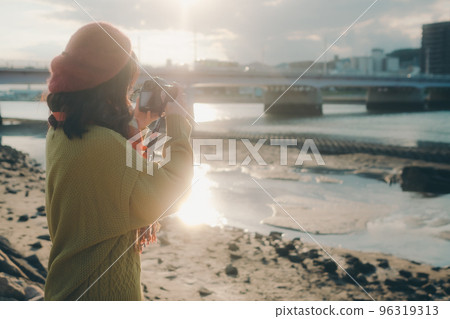 Photo of a young woman taking pictures with a camera on a riverbed 96319313