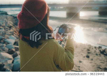 Photo of a young woman taking pictures with a camera on a riverbed 96319443
