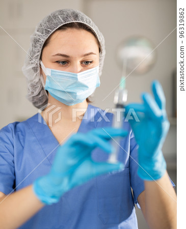 Female nurse in mask holding syringe for injection 96319862