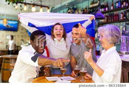 Cheerful males and females celebrating spots team victory, waving flag of Russia in bar 96319864