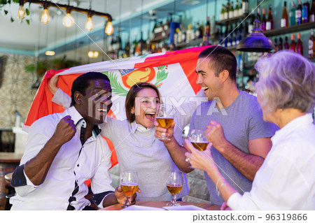 Cheerful multiracial footbal fans waving the flag of Peru while drinking beer and watching tournament in sport bar 96319866
