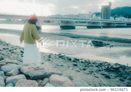 Photo of a young woman taking pictures with a single lens reflex camera on a riverbed Photo of a young woman taking pictures with a single lens reflex camera on a riverbed 96319871