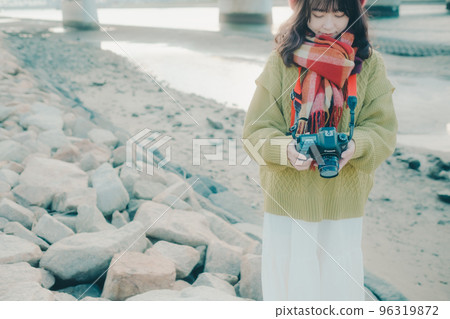 Photo of a young woman taking pictures with a single lens reflex camera on a riverbed Photo of a young woman taking pictures with a single lens reflex camera on a riverbed 96319872