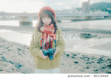 Photo of a young woman taking pictures with a single lens reflex camera on a riverbed Photo of a young woman taking pictures with a single lens reflex camera on a riverbed 96319880