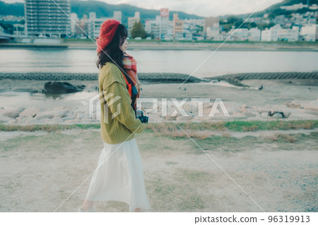 Photo of a young woman taking pictures with a single lens reflex camera on a riverbed 96319913