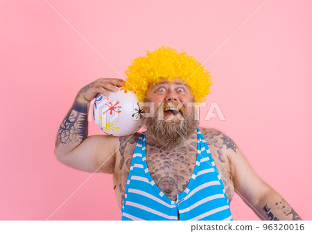 Fat amazed man with beard and wig play with the ball 96320016