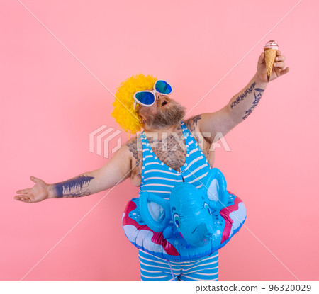 Fat man with beard and wig eats an icecream 96320029