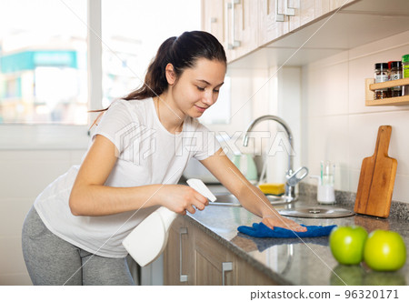 Attractive smiling young woman cleaning kitchen counter Attractive smiling young woman cleaning kitchen counter 96320171