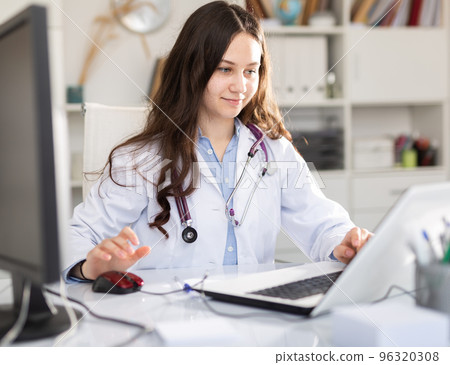 Portrait of female doctor who is working with laptop and documents Portrait of female doctor who is working with laptop and documents 96320308