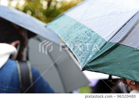People holding umbrellas at a resort on a rainy day. Unfortunately, even though it's a special holiday, there are many raindrops on the umbrellas. People holding umbrellas at a resort on a rainy day. Unfortunately, even though it's a special holiday, there are many raindrops on the umbrellas. 96320480