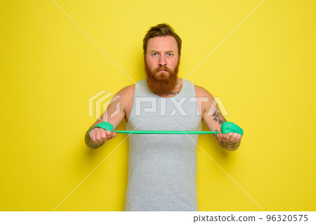 Man with beard and tattoos trains with a rubber band Man with beard and tattoos trains with a rubber band 96320575