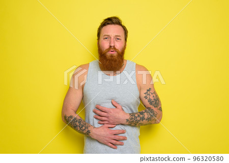 Suffering man with beard and tattoos has stomach ache 96320580