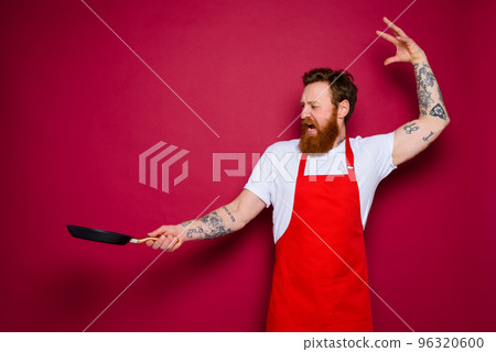angry chef with beard and red apron cooks with pan angry chef with beard and red apron cooks with pan 96320600