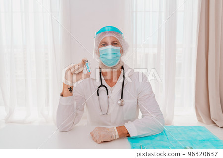 Doctor with mask and syringe is ready to administer the vaccine against covid 19 Doctor with mask and syringe is ready to administer the vaccine against covid 19 96320637