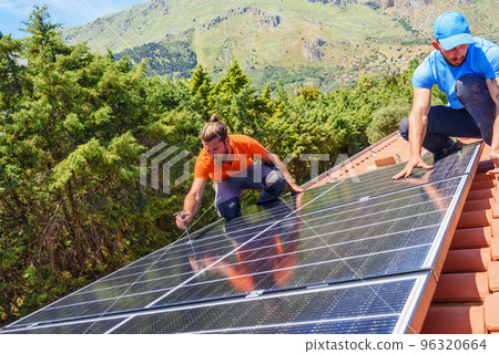 Workers assemble energy system with solar panel for electricity and hot water 96320664