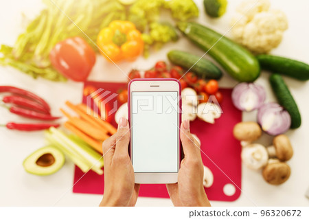 Cook follows a recipe of vegetables from the smartphone 96320672